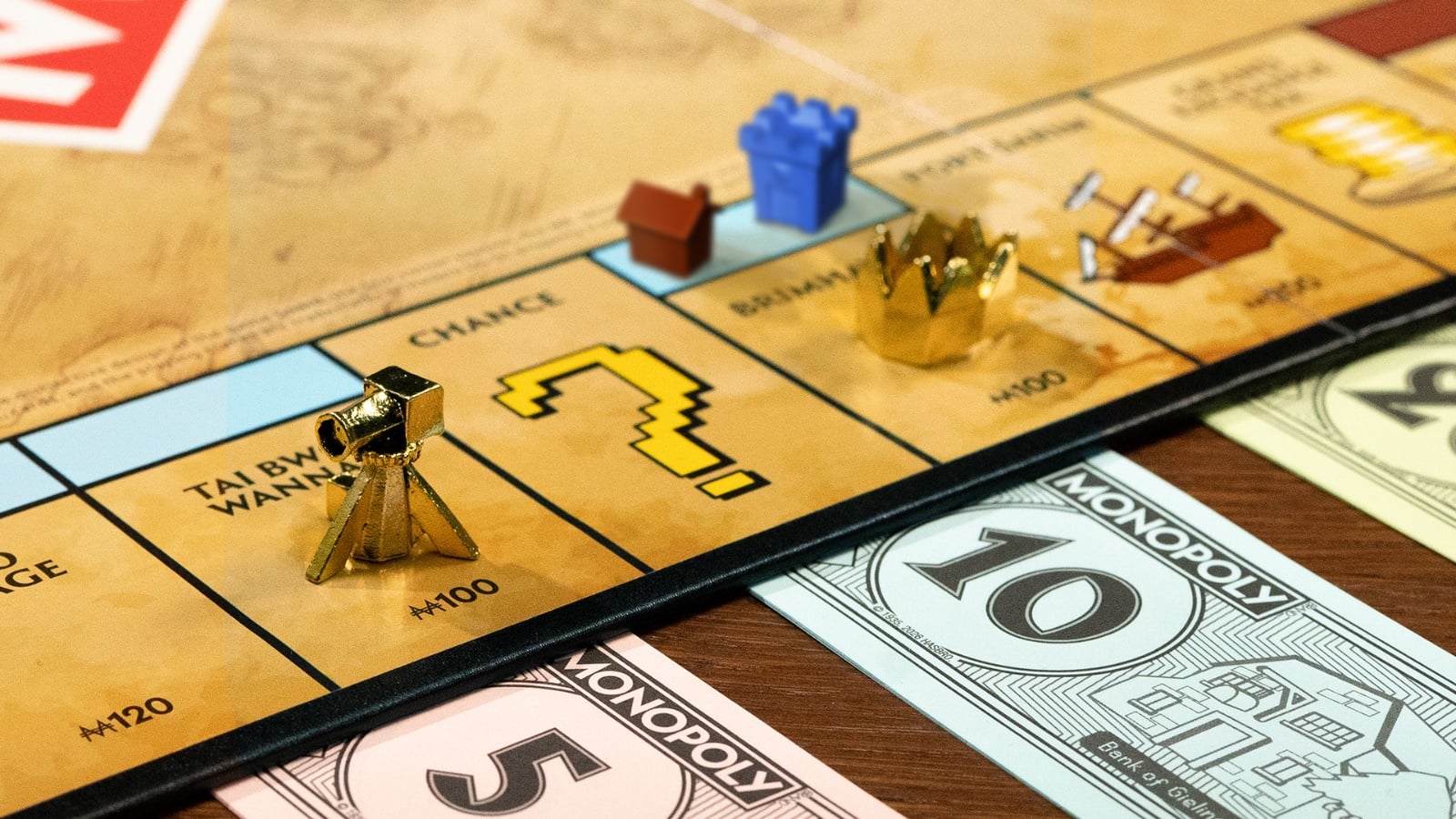 Inside the RuneScape Monopoly Edition showing the board, GP currency, collectible tokens, property cards, houses, castles, and game accessories.